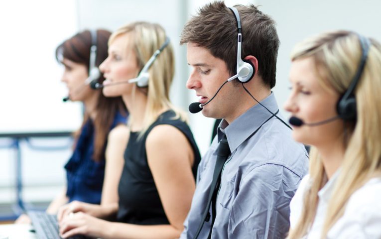 Attractive young man working in a call center with his colleagues